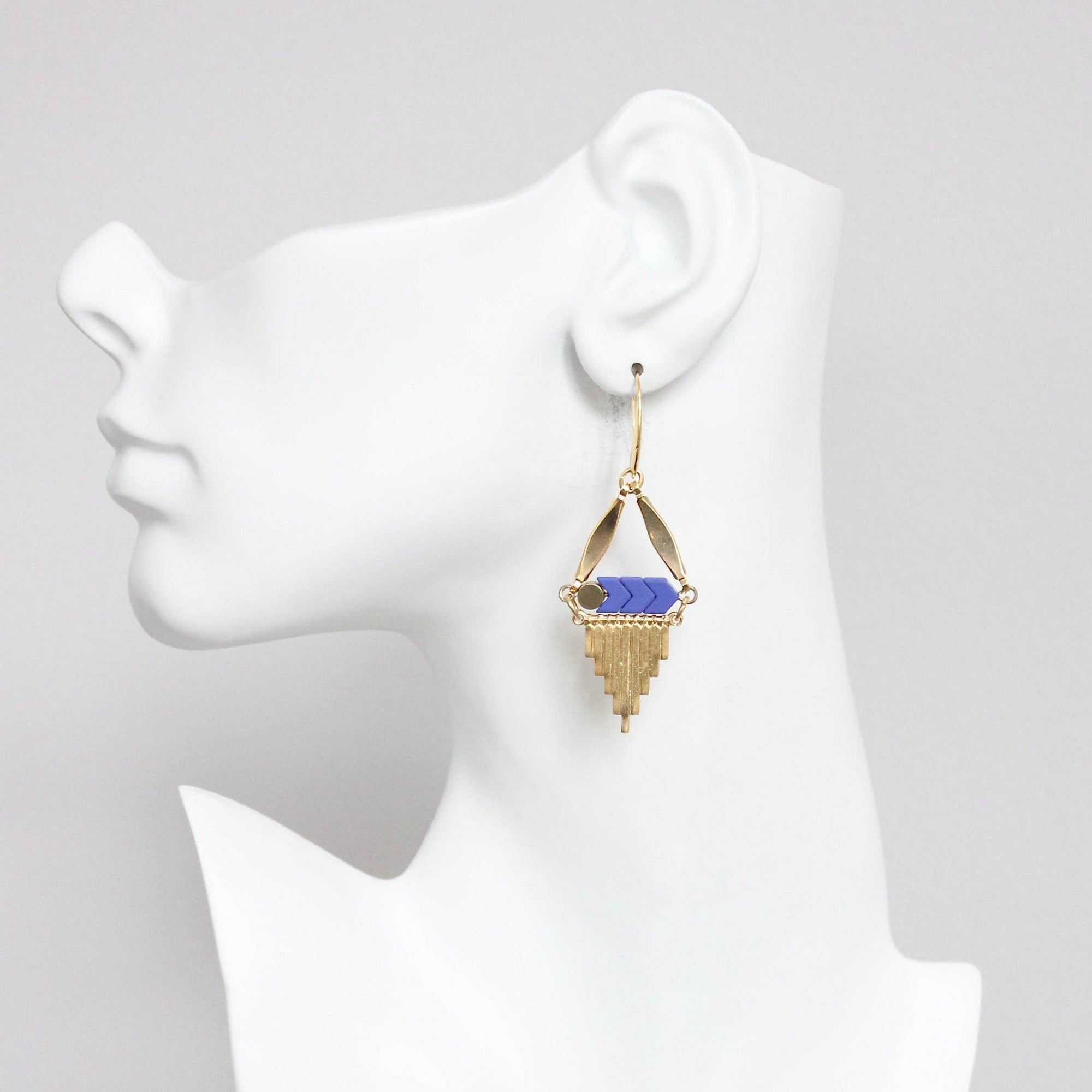 Gold earring with blue gemstone on a mannequin ear
