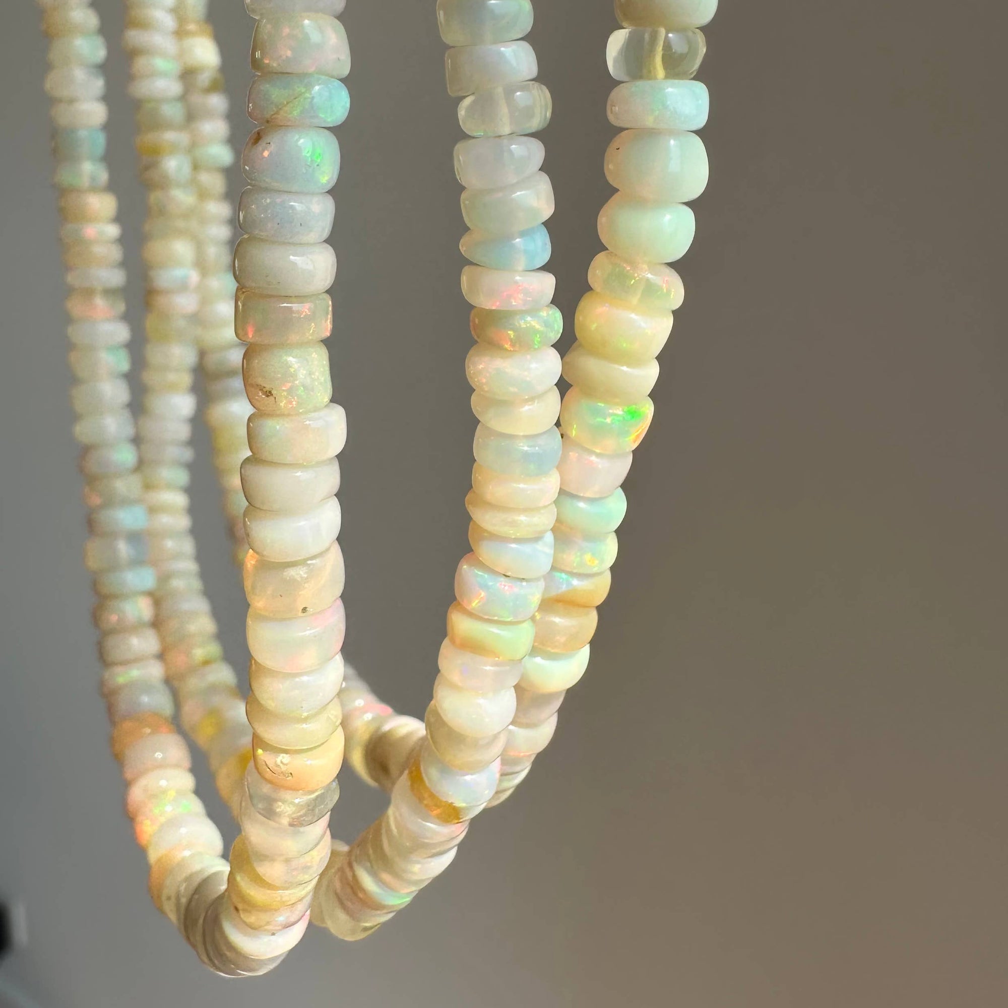 Three strands of opal beads on a gray background