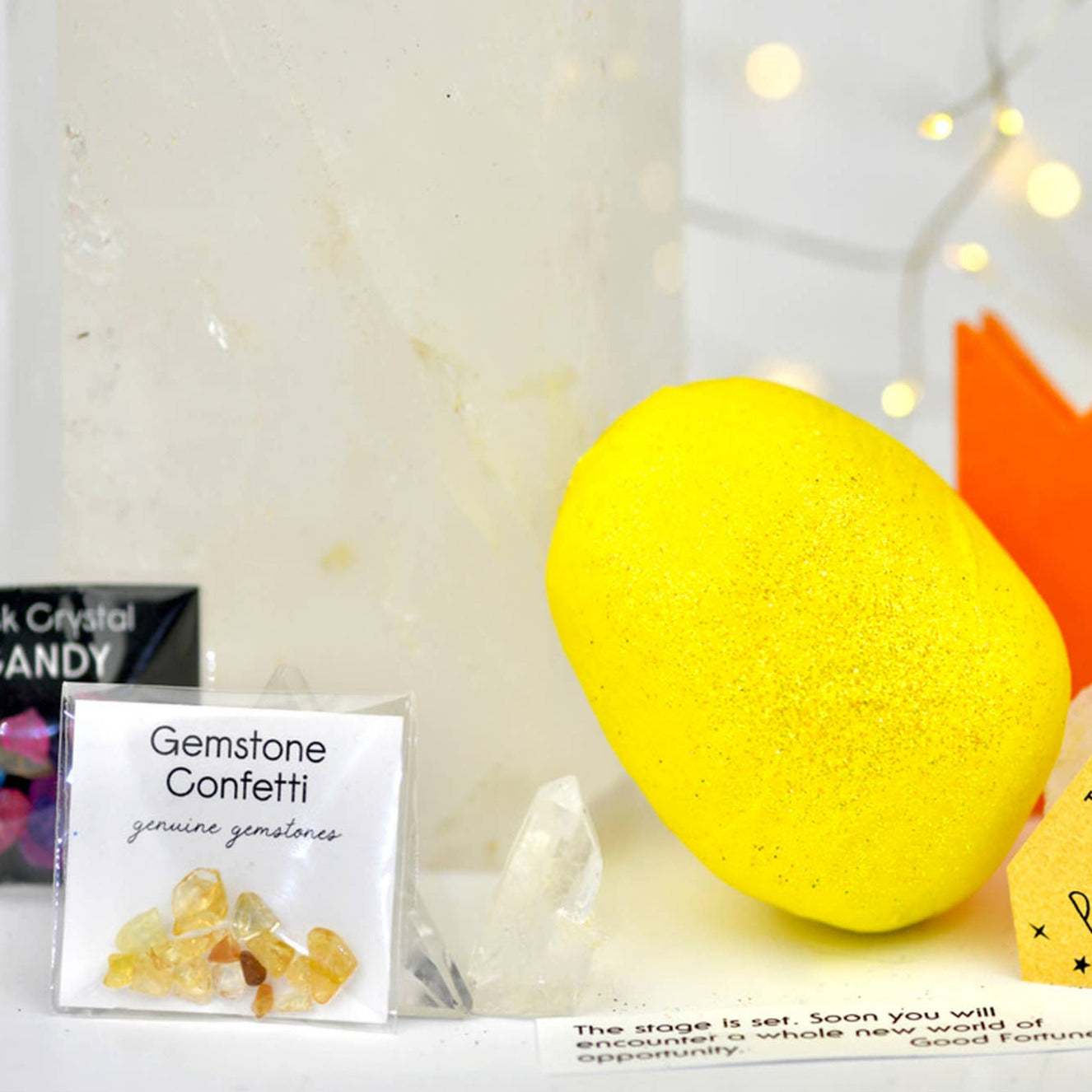 Yellow surprise ball with gemstone confetti and other items on a white surface.