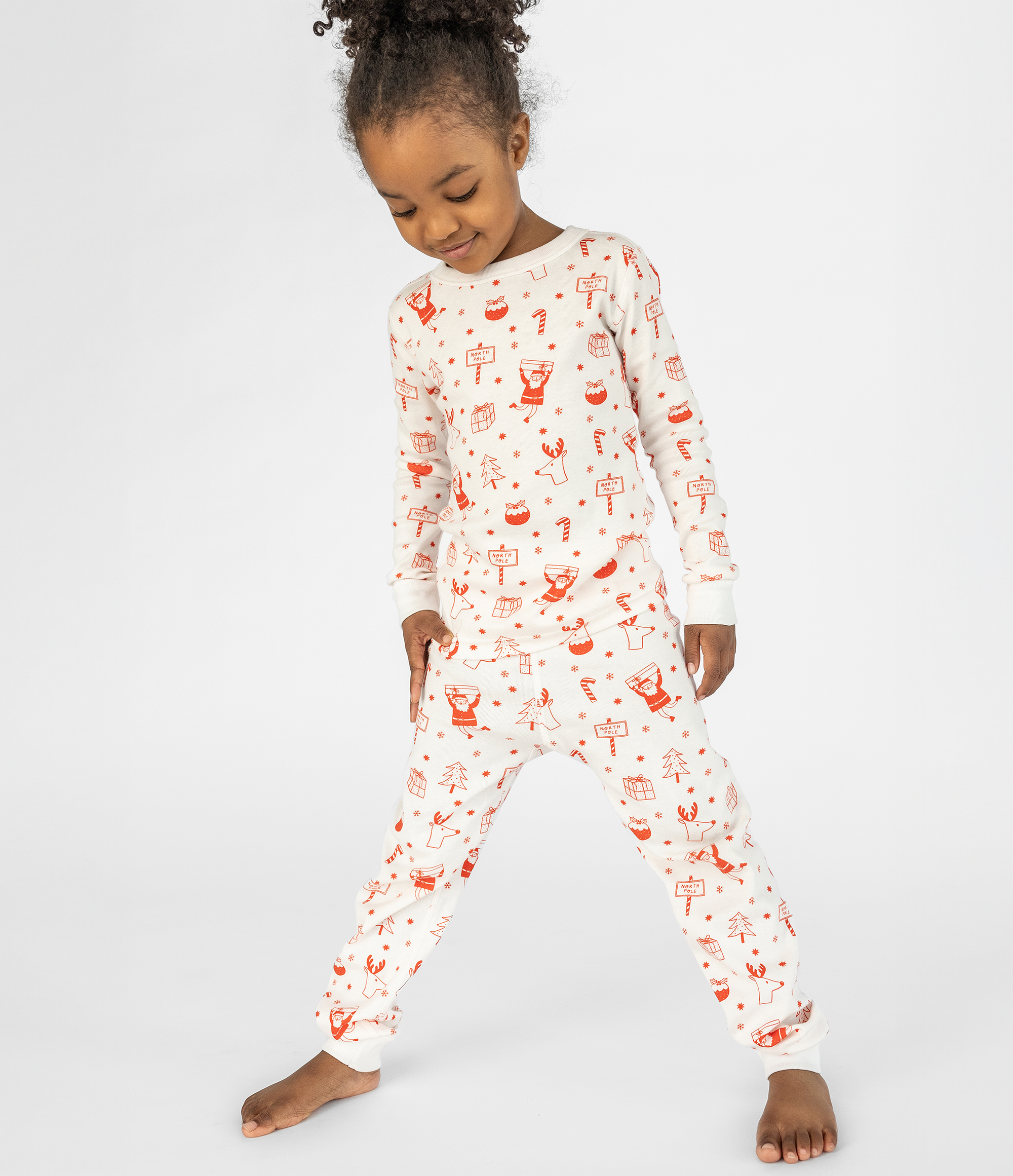 Child wearing a white onesie with red patterns on a white background