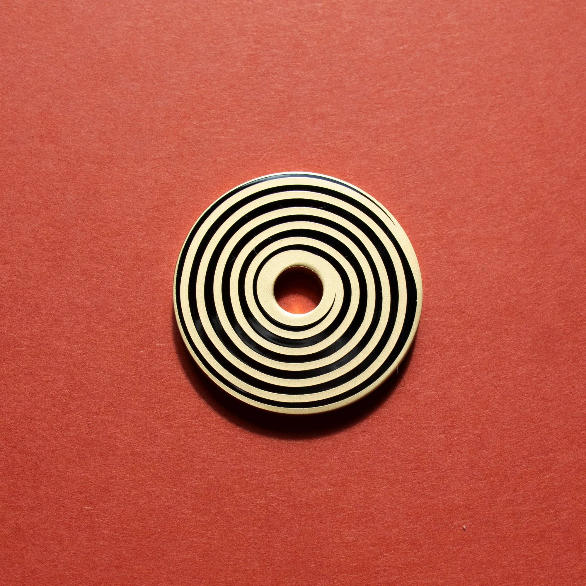 Circular object with concentric black and beige rings on a red background