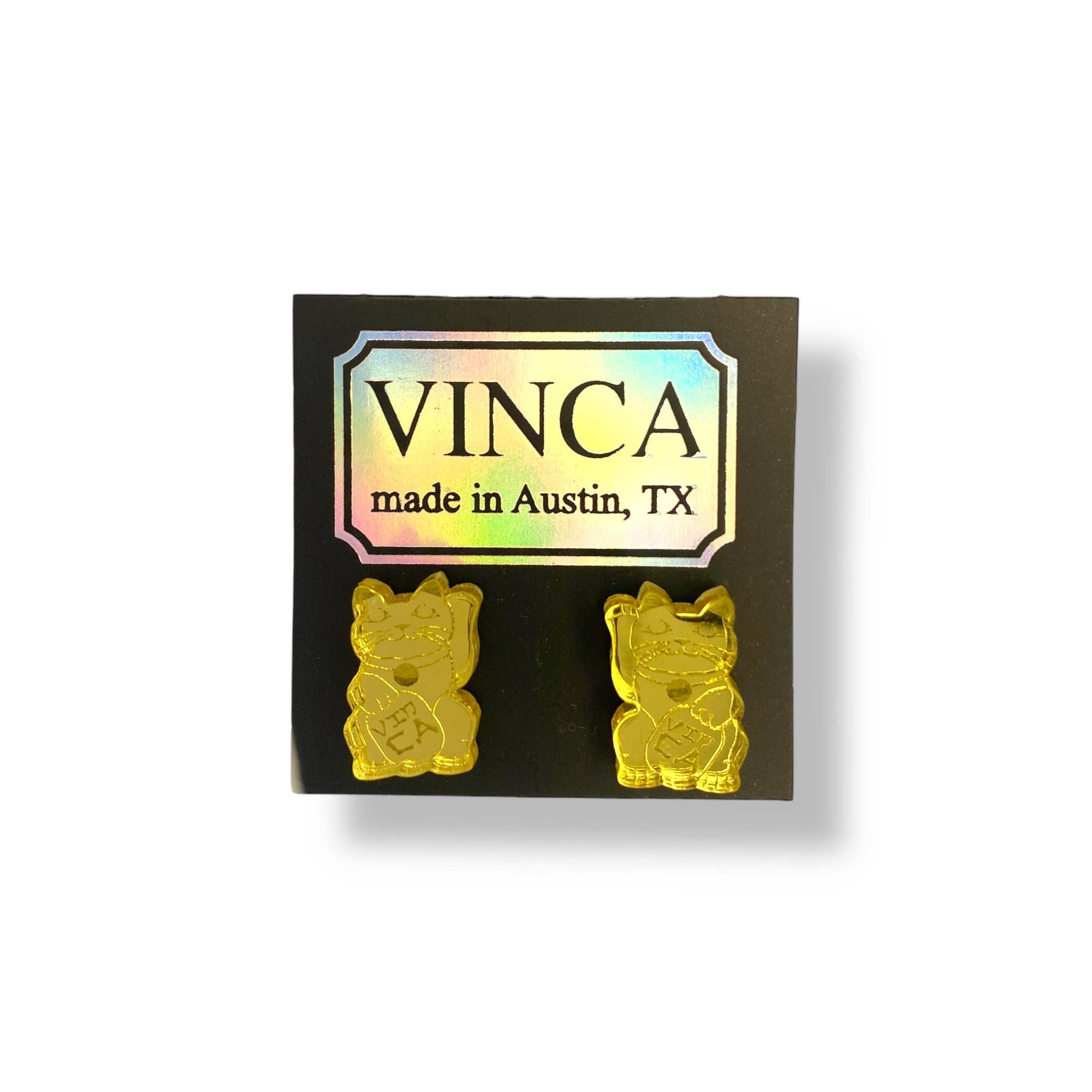 Gold cat-shaped earrings on a black card with 'VINCA' branding.