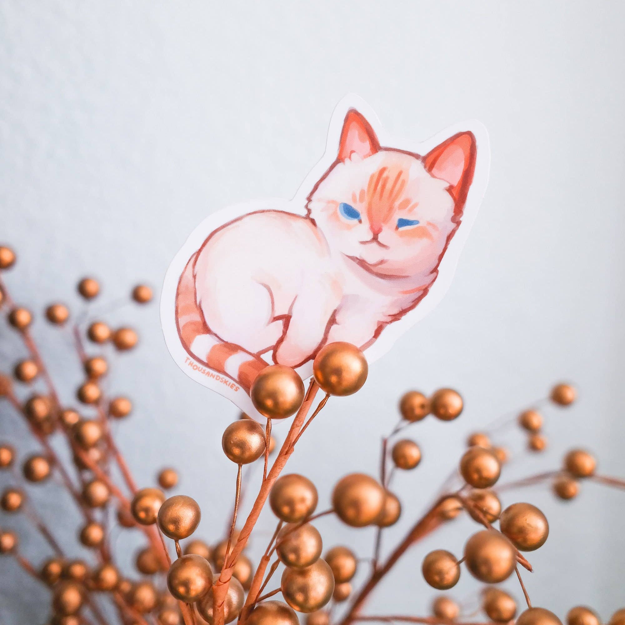 Illustration of a cat sitting among gold berries on a light blue background