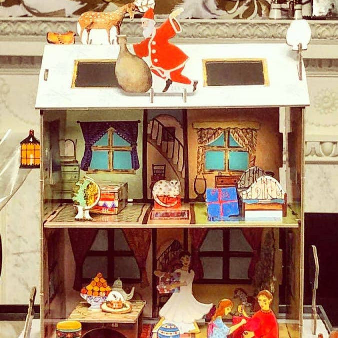 Detailed model of a dollhouse with furniture and decorative items inside.