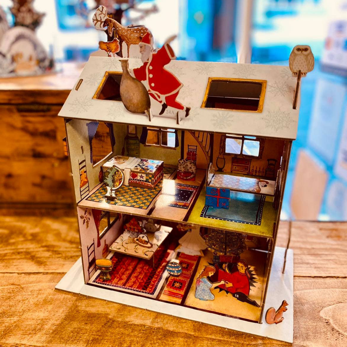Detailed model of a dollhouse with various rooms and furniture on a wooden surface.