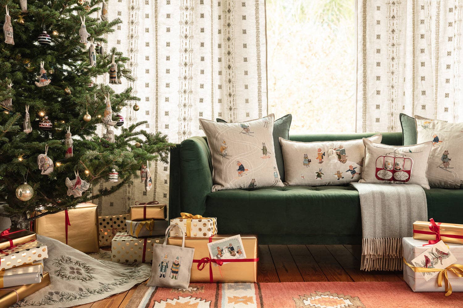 Living room with a decorated Christmas tree and green sofa with patterned cushions.