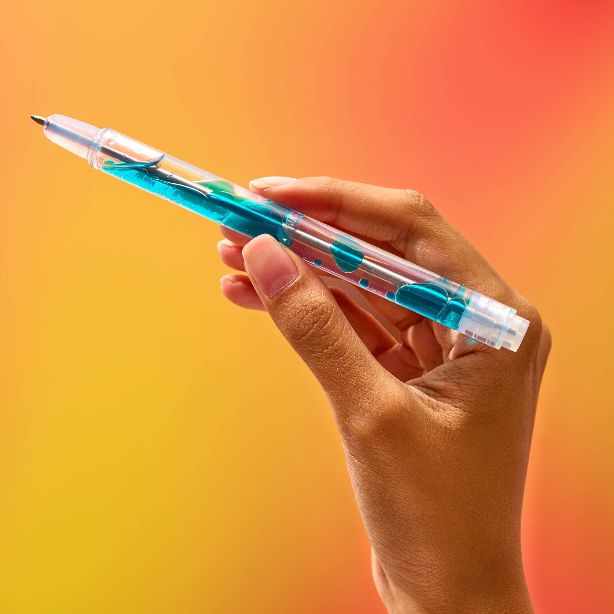 Hand holding a transparent pen with blue ink on an orange gradient background
