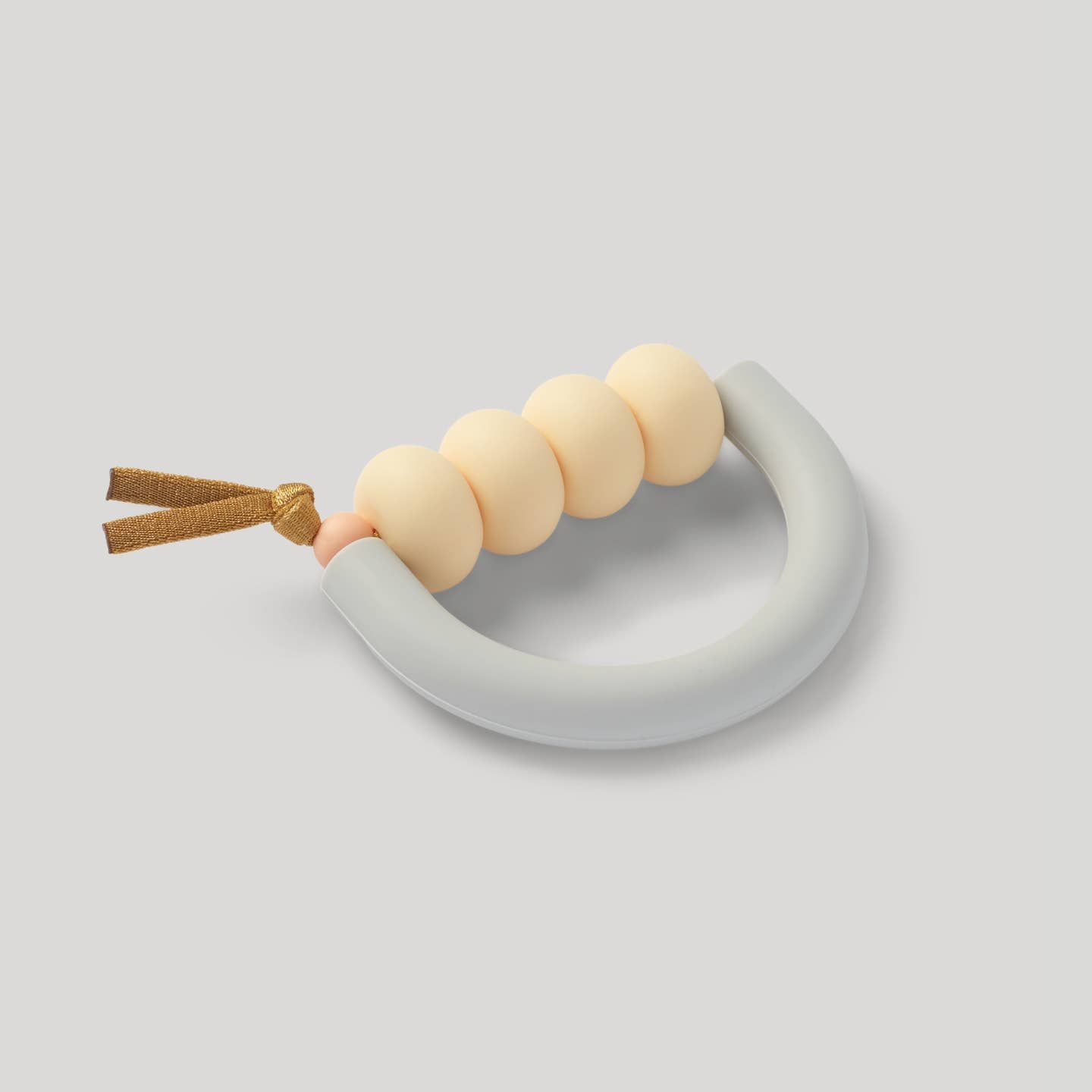 Teething ring with beige beads and a gray handle on a light gray background