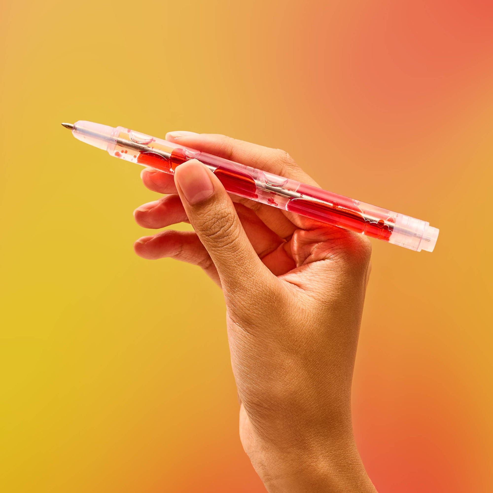Hand holding a red pen against a gradient yellow to orange background