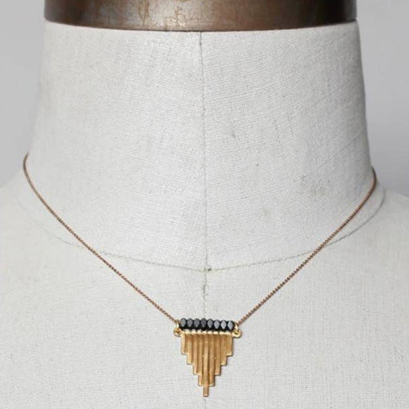 Necklace with a geometric pendant on a mannequin bust against a neutral background