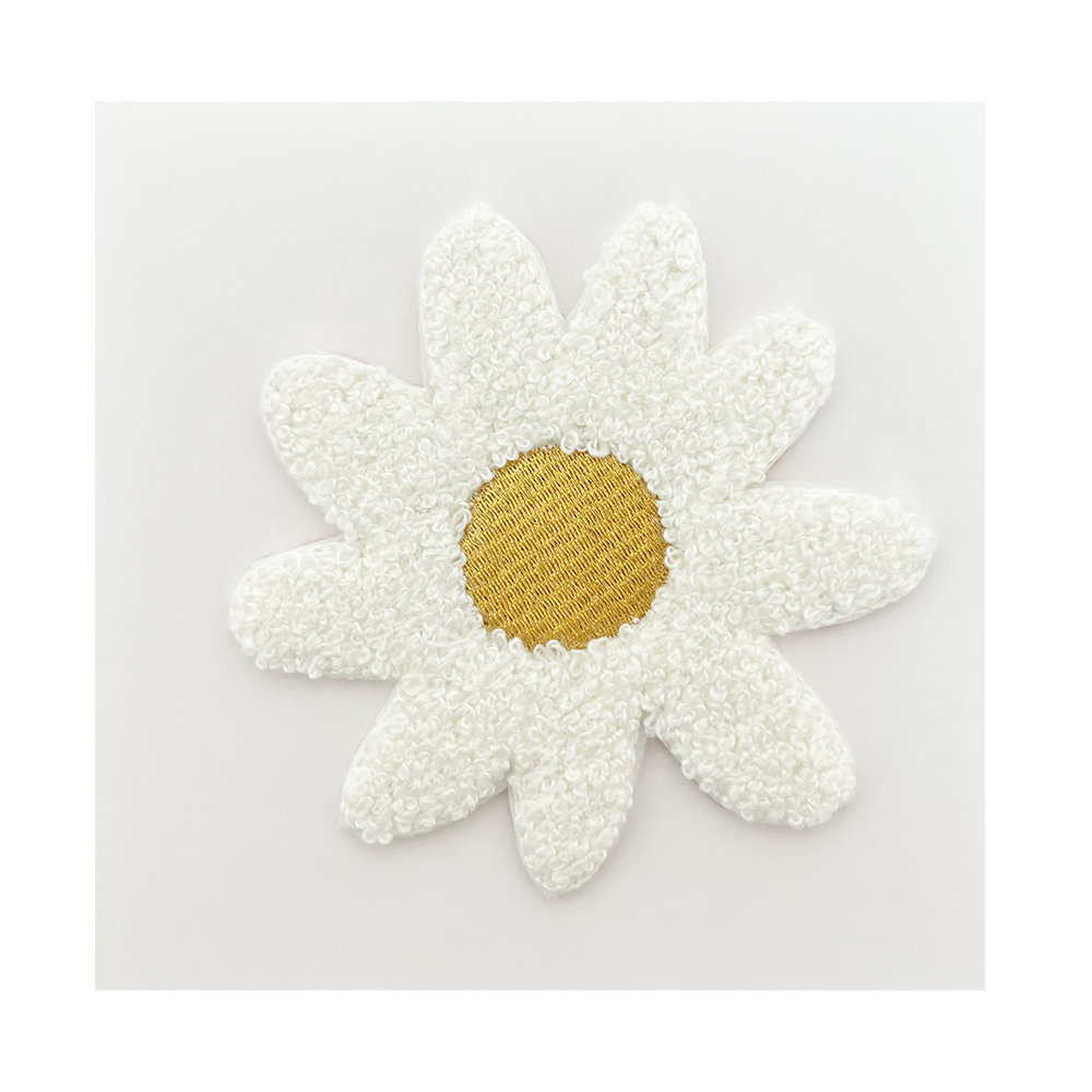White flower-shaped object with a gold center on a light gray background