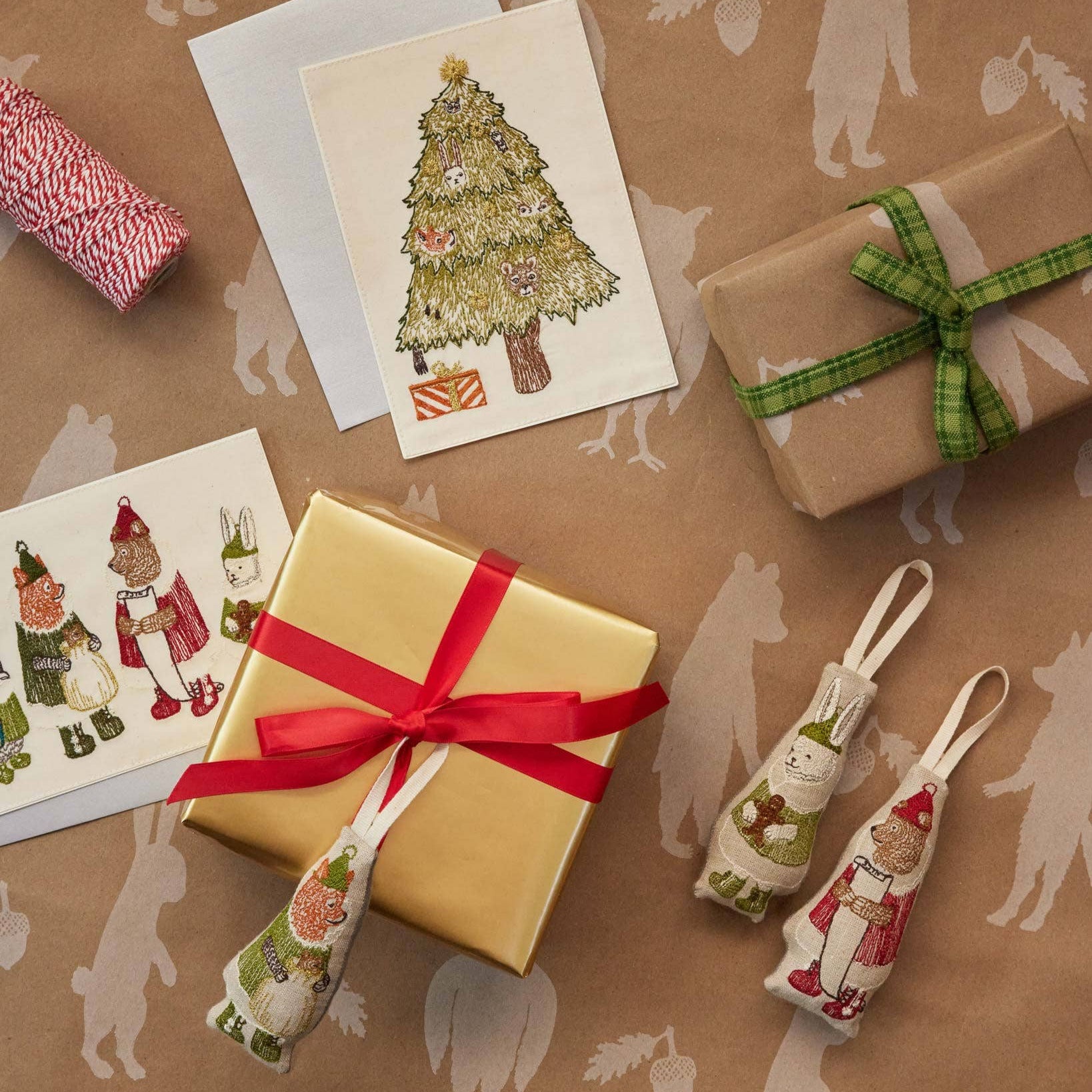 Gifts wrapped in brown paper with decorative ribbons and cards on a patterned surface.