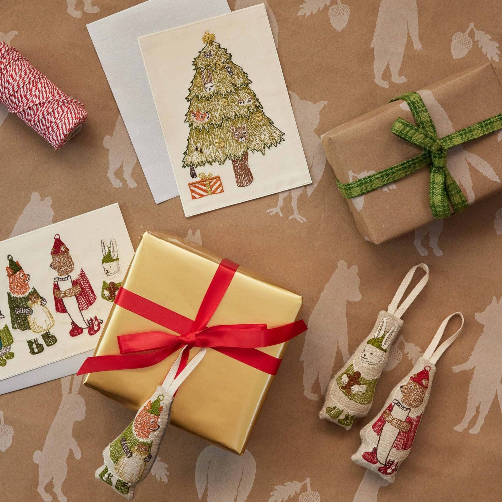 Gifts wrapped in brown paper with decorative ribbons and cards on a patterned surface.