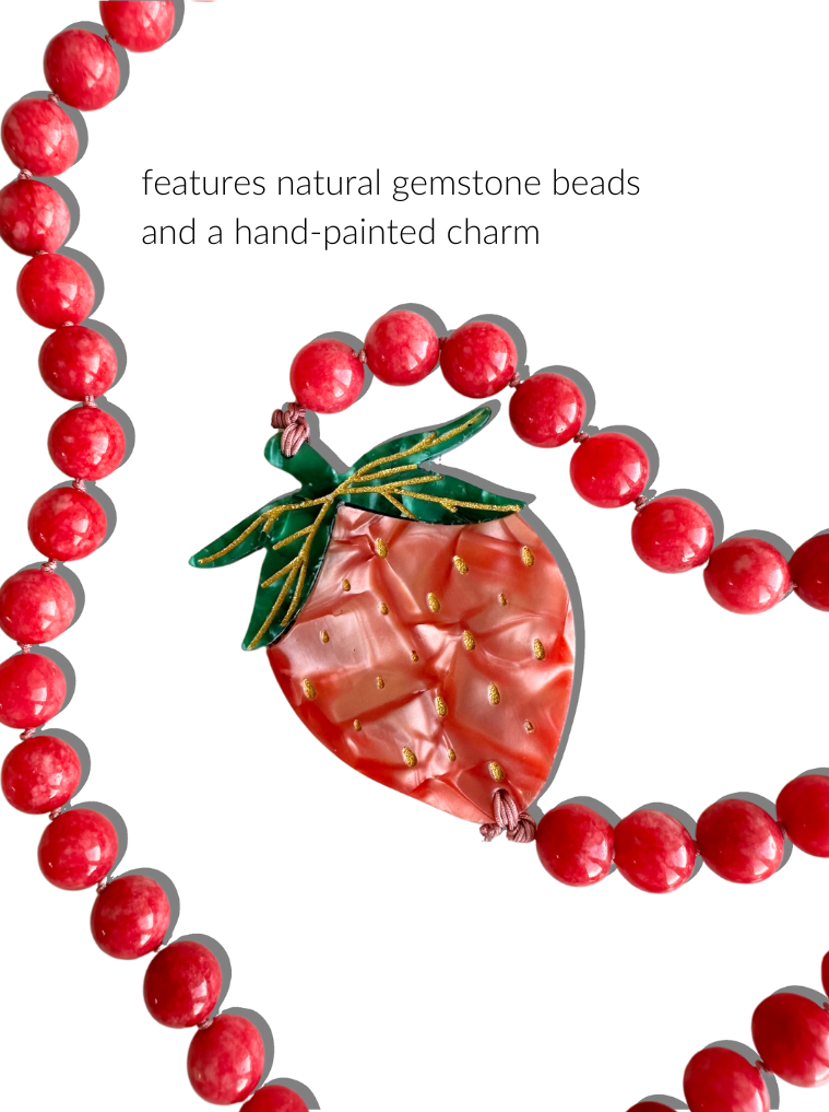 Necklace with red beads and a hand-painted strawberry charm on a white background