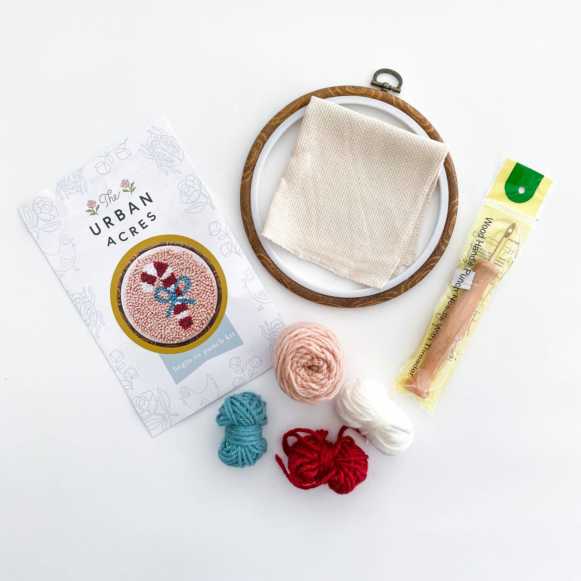 Embroidery hoop with fabric, yarn, and a book on a white background