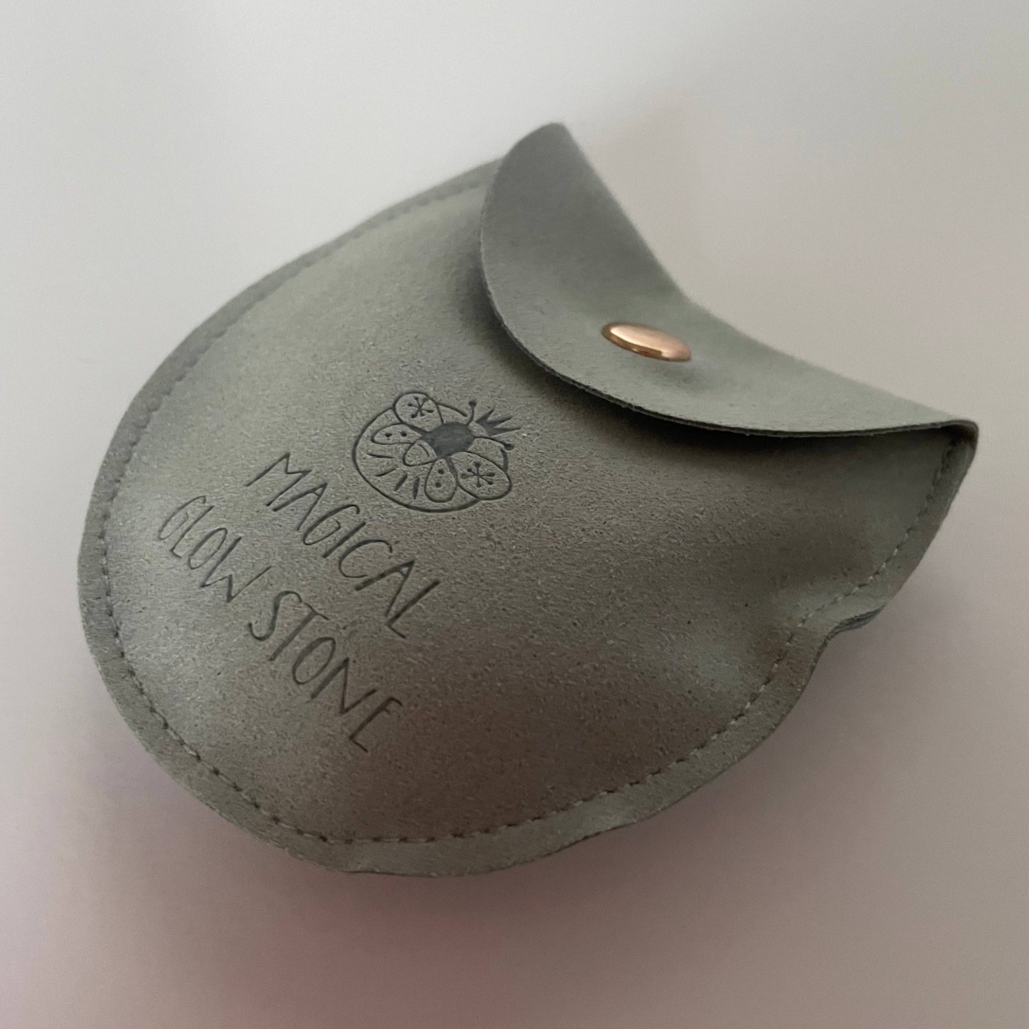Gray leather pouch with 'Magical Glow Stone' text and logo on a light gray background