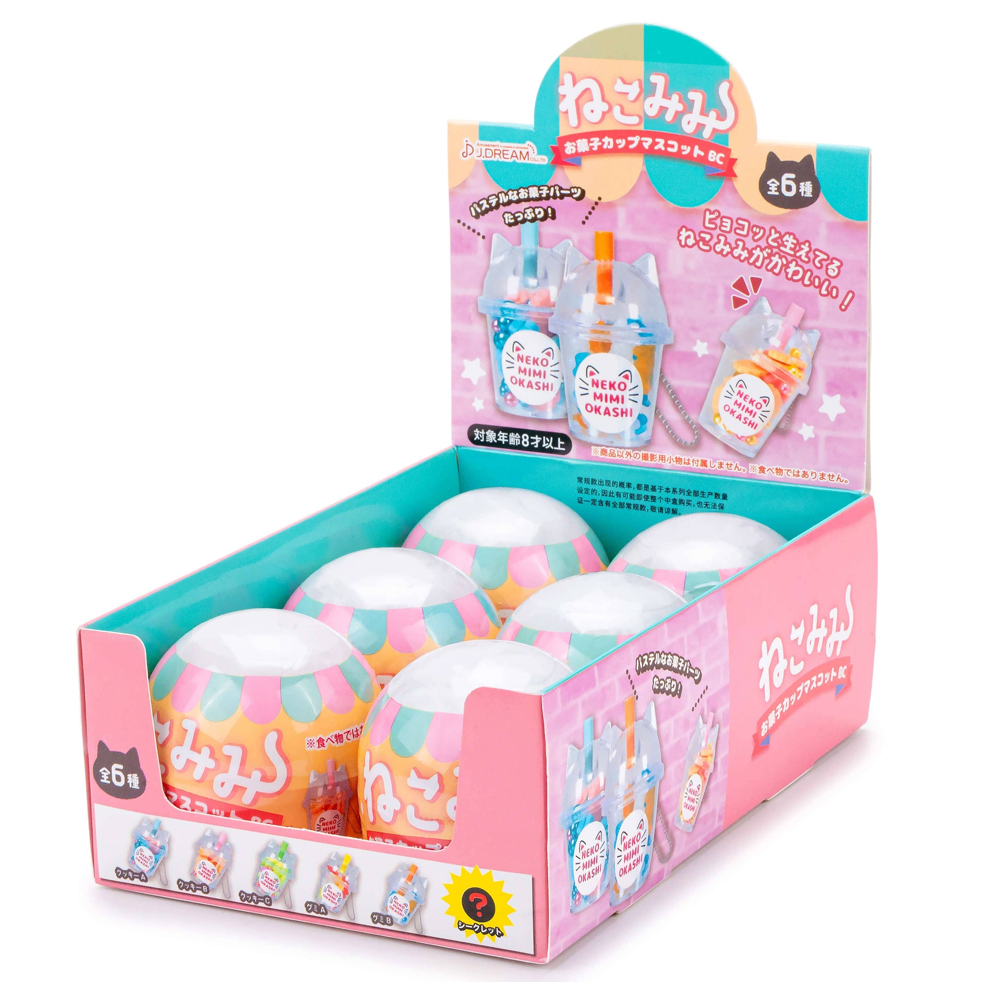 Display box of colorful small capsules with Japanese text on a white background