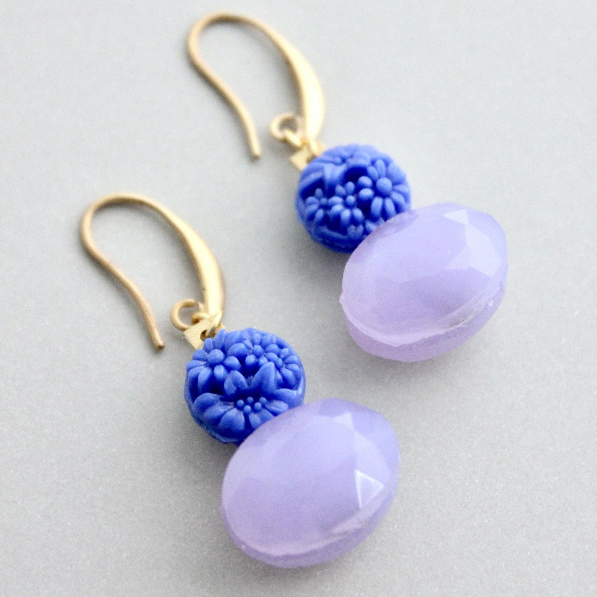 Pair of earrings with purple and blue beads on a light gray background