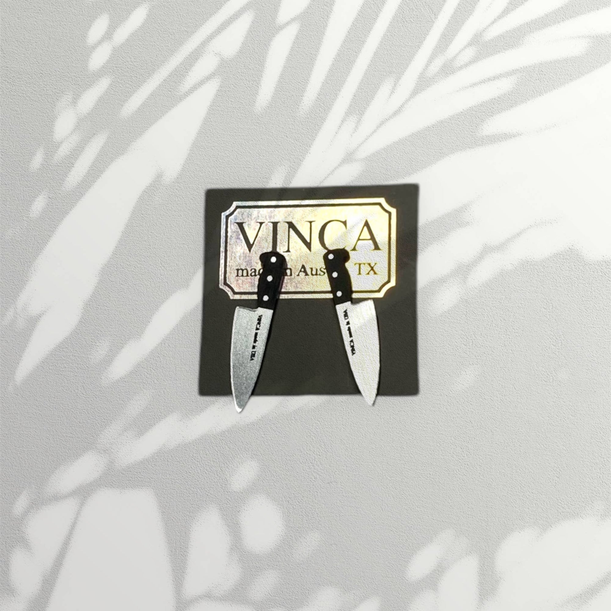 Two small knives on a black card with 'VINCA' branding against a light background