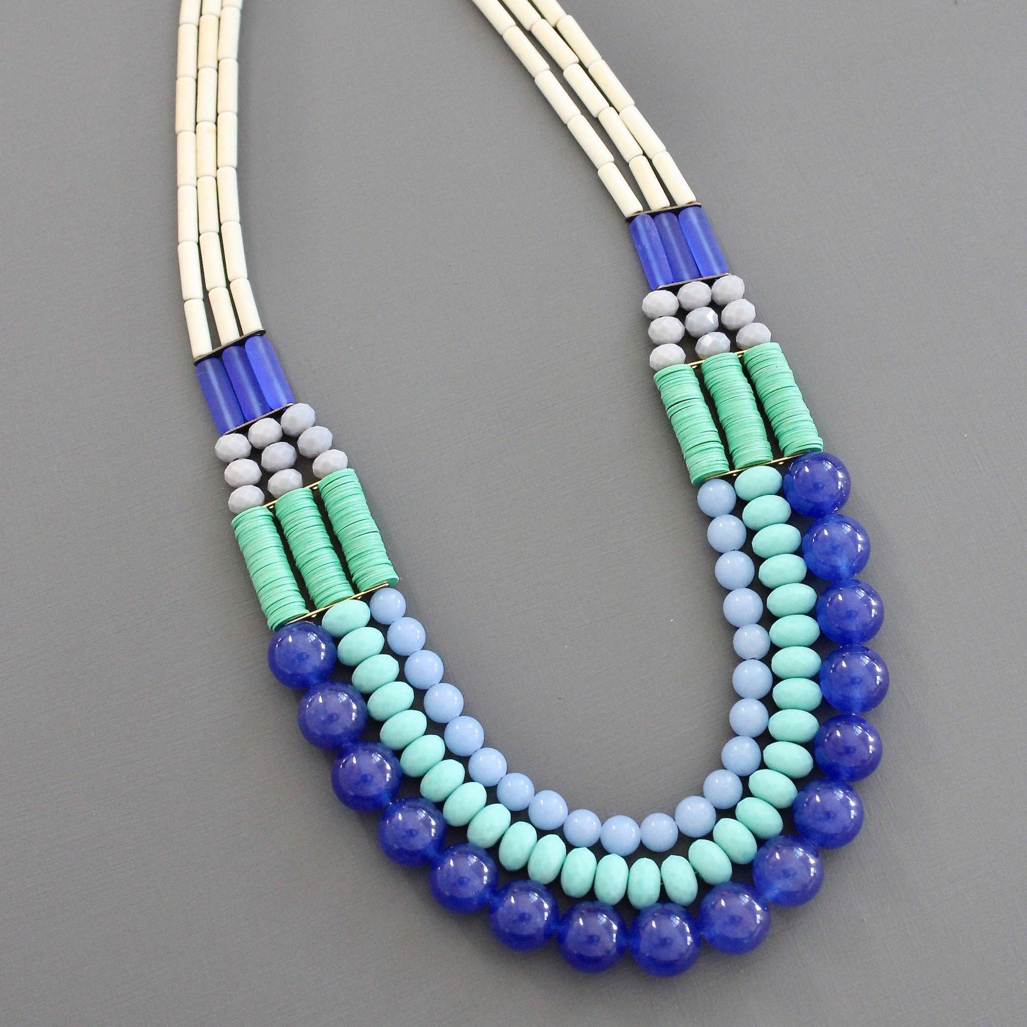 Multicolored beaded necklace with gold clasp on a gray background