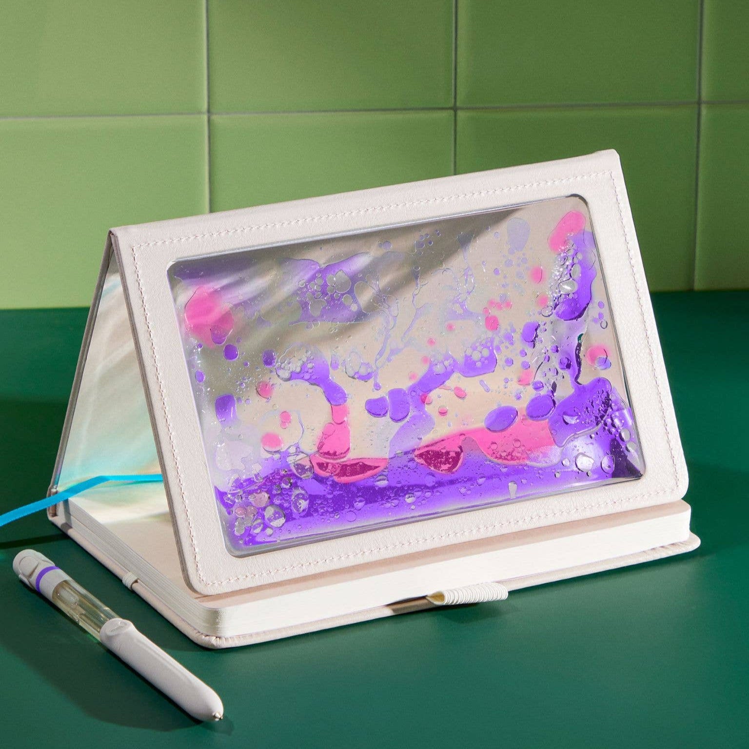 Tablet with a colorful screen in a white stand on a green surface with a green tiled wall background