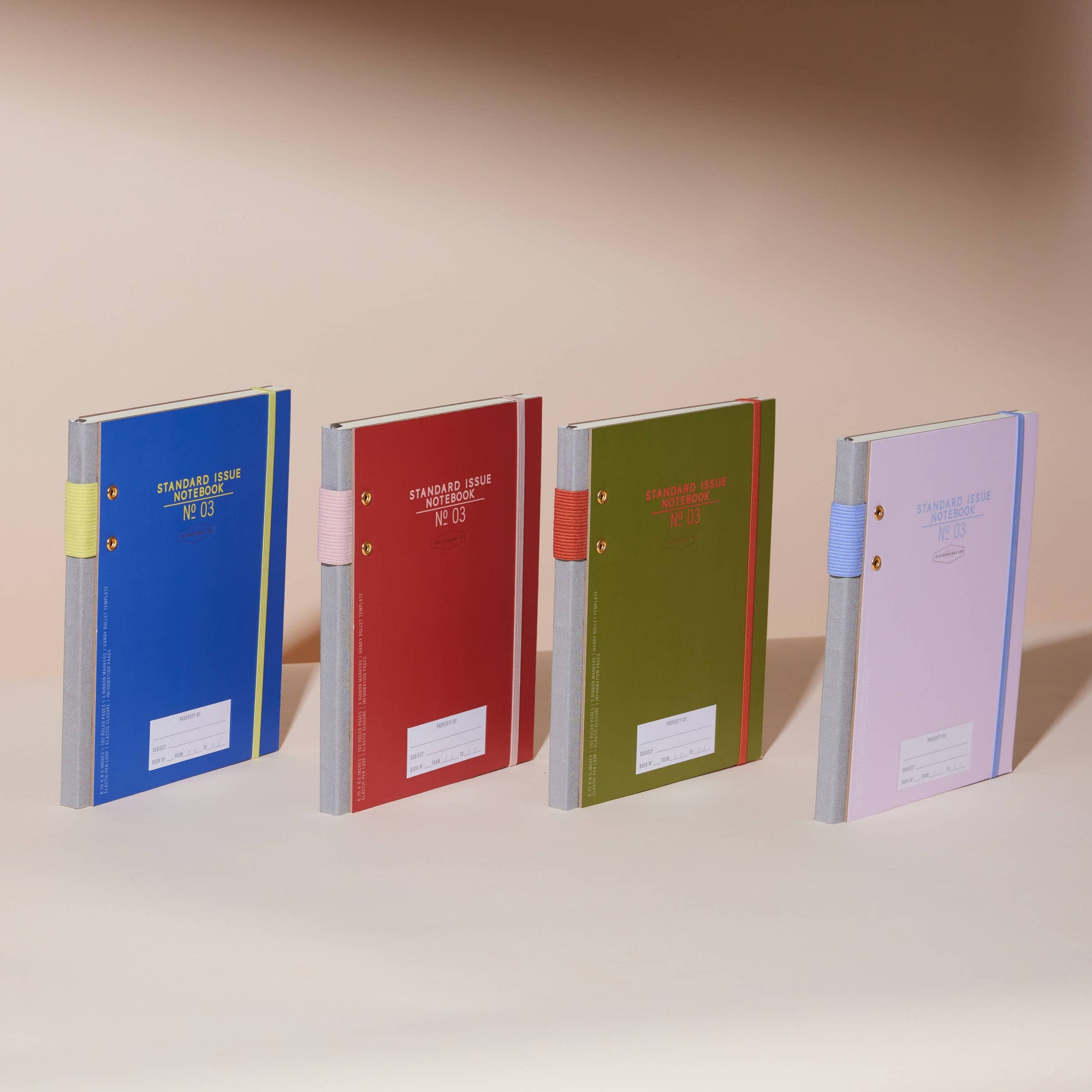 Four colorful notebooks on a shelf with a neutral background