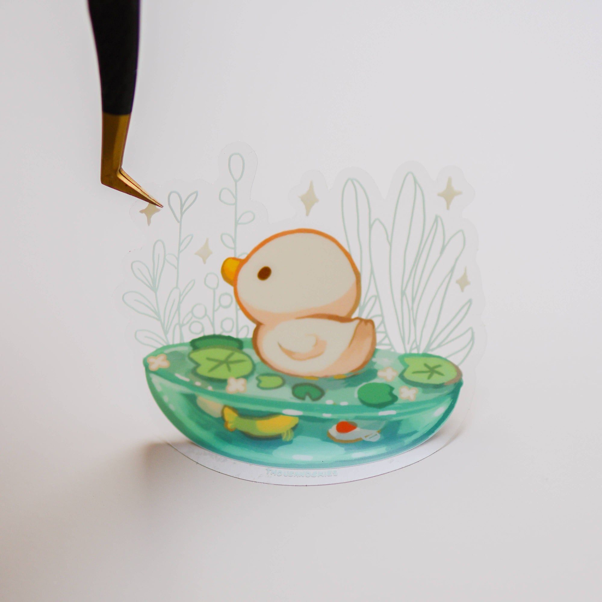 Decorative item with a duckling on water lilies and plants on a white background