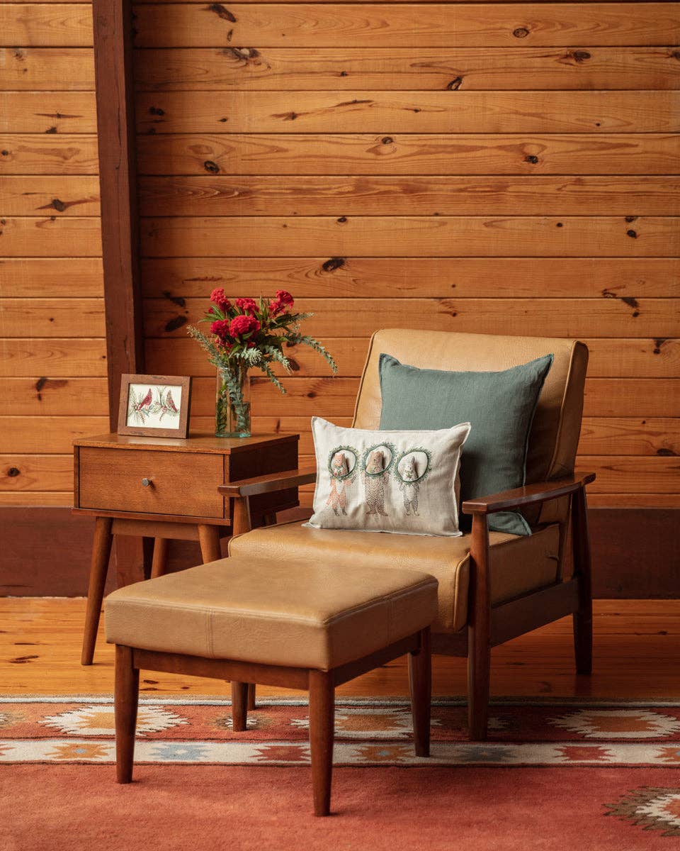 Wooden armchair with ottoman, side table, and decorative items against a wooden wall.
