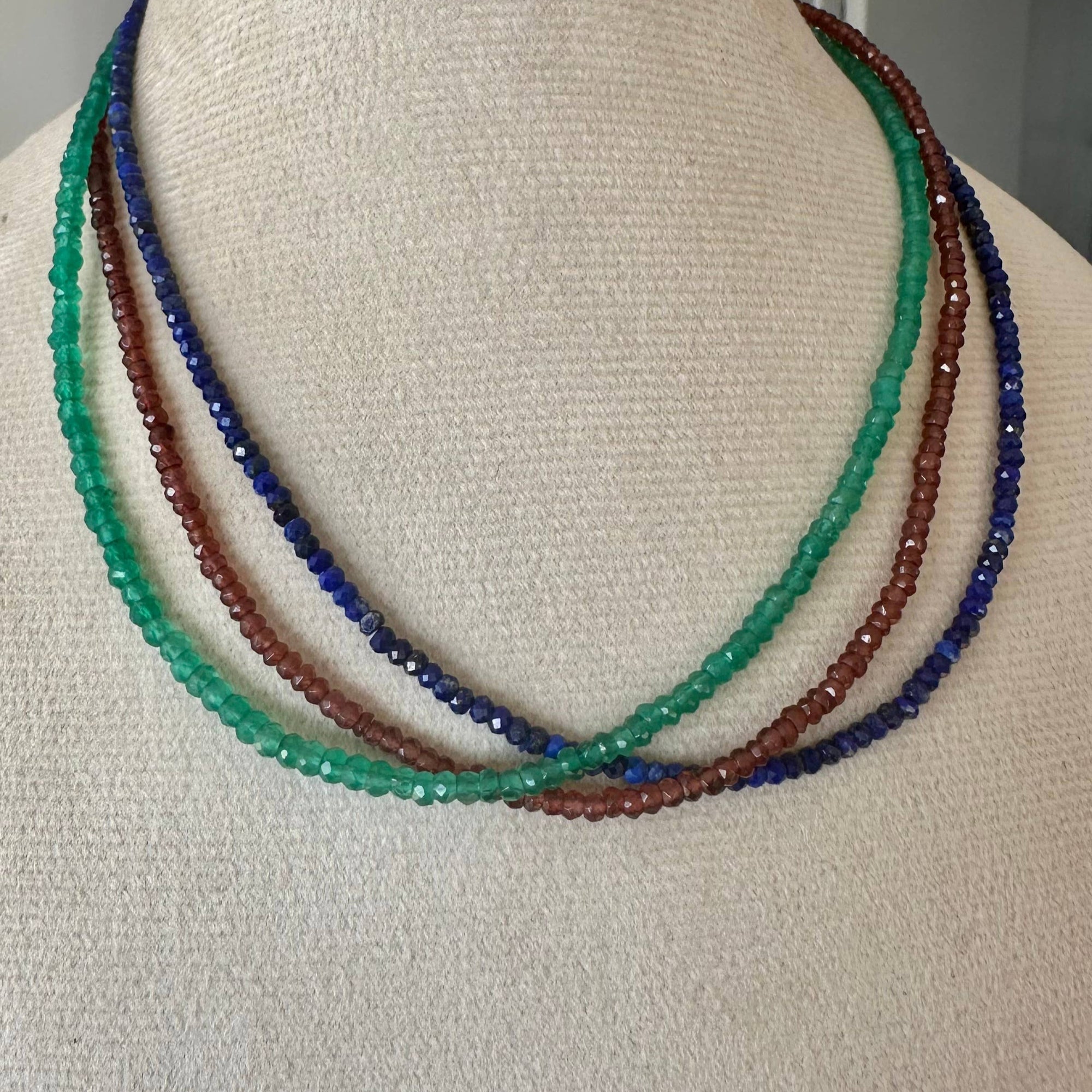 Necklace with green, red, and blue beads on a mannequin bust.