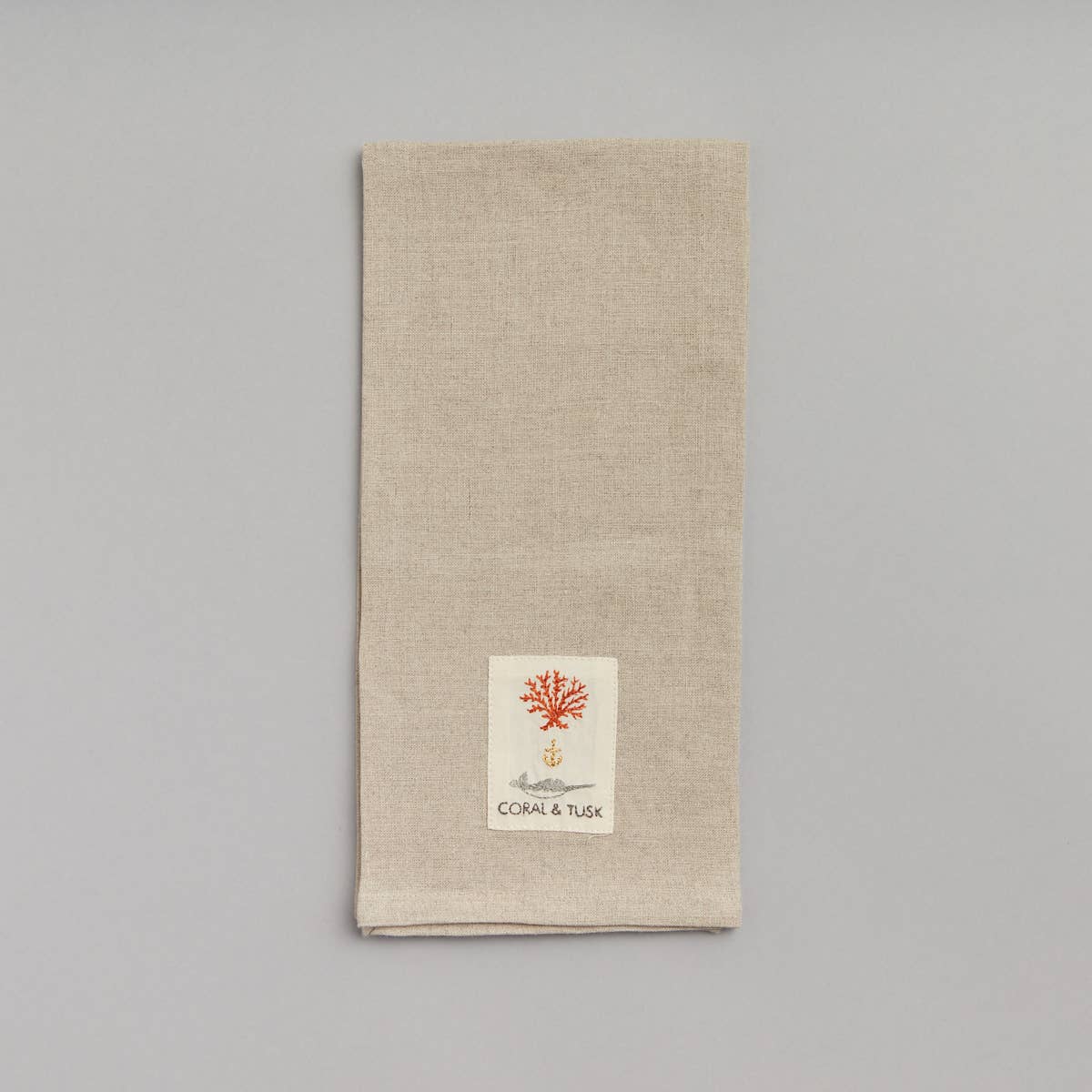 Beige towel with a small logo on a gray background