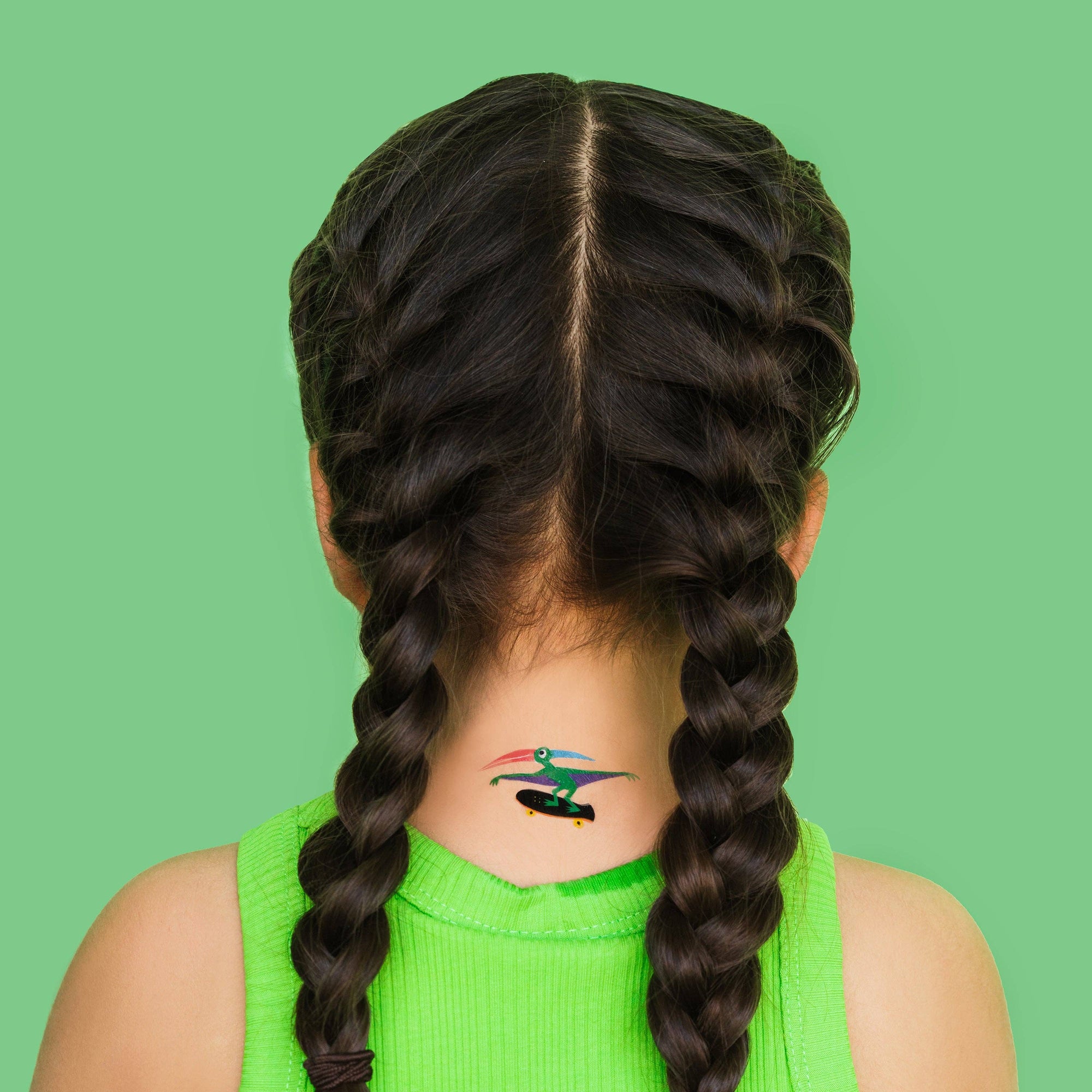 Person with braided hair and a tattoo on a green background