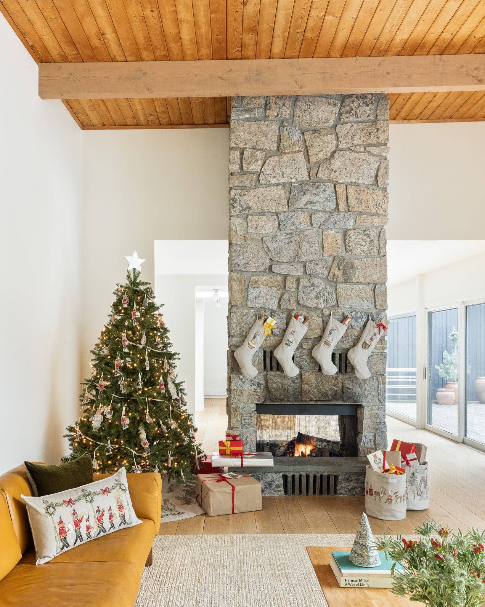 Living room with stone fireplace, Christmas tree, and stockings.