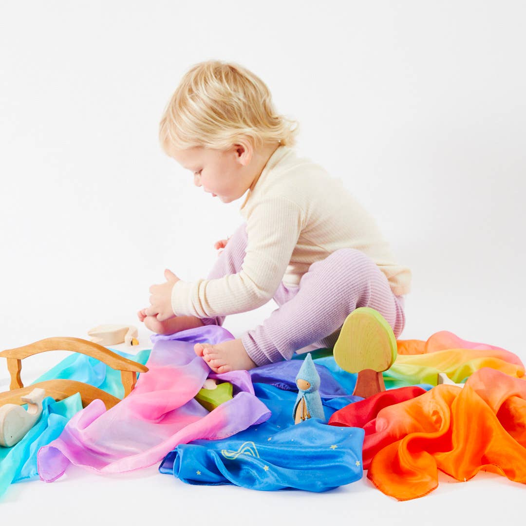 Child playing with colorful fabric on a white background