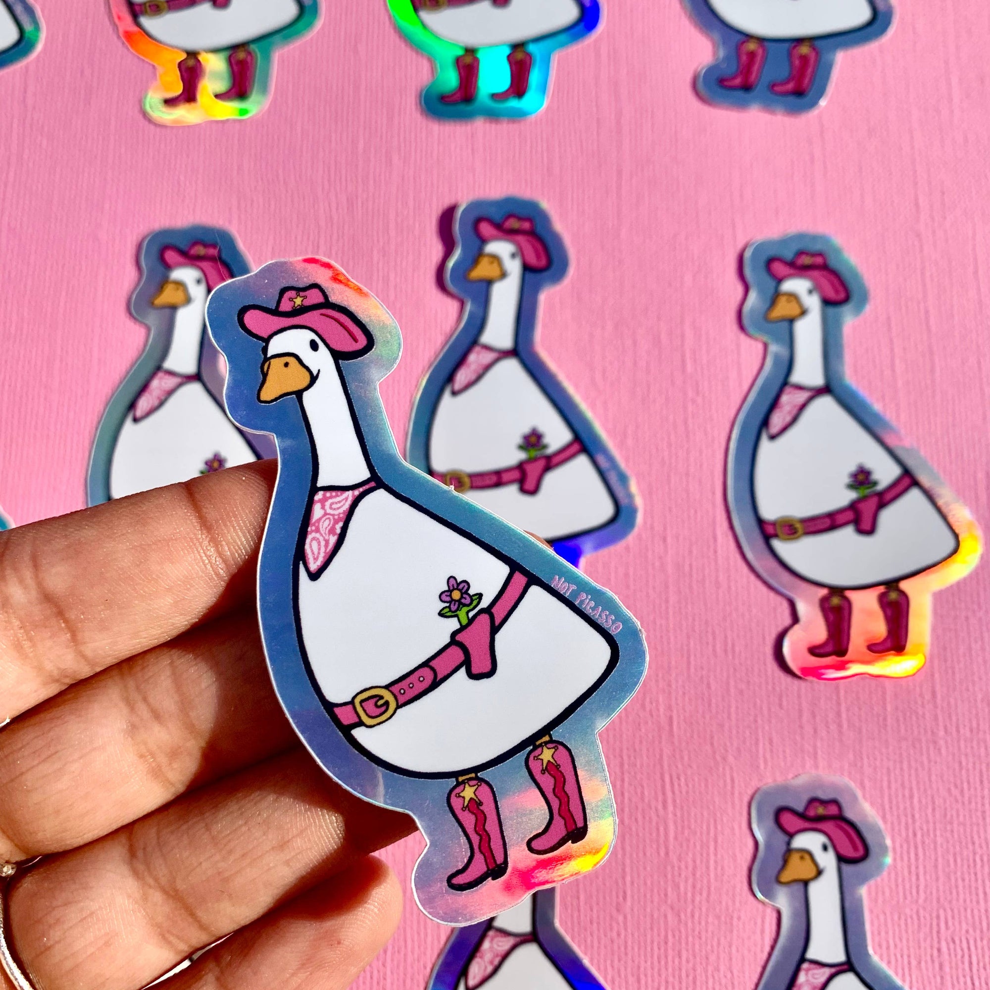 Holographic duck stickers on a pink background with a hand holding one sticker.