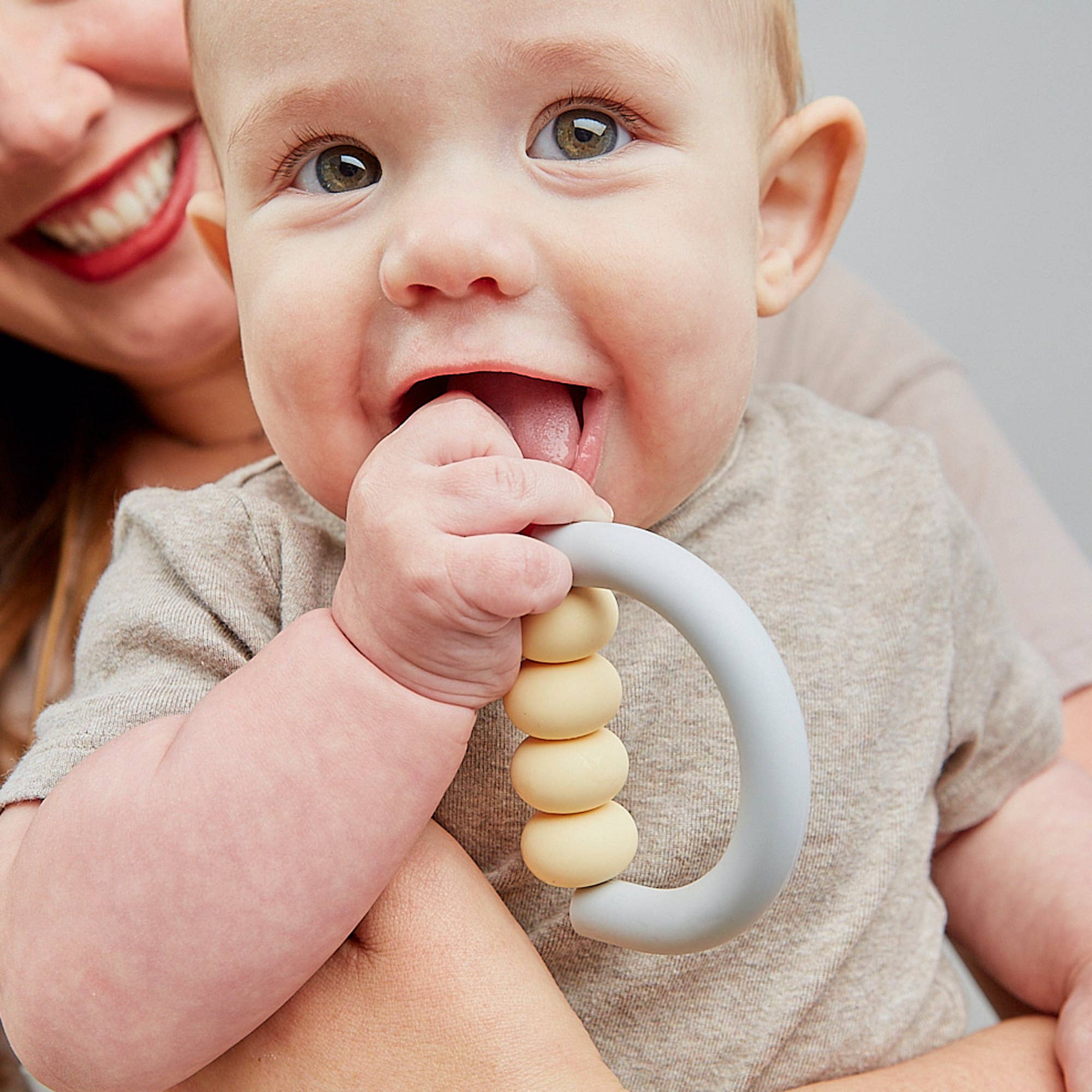 Baby holding a teething ring with a blurred background