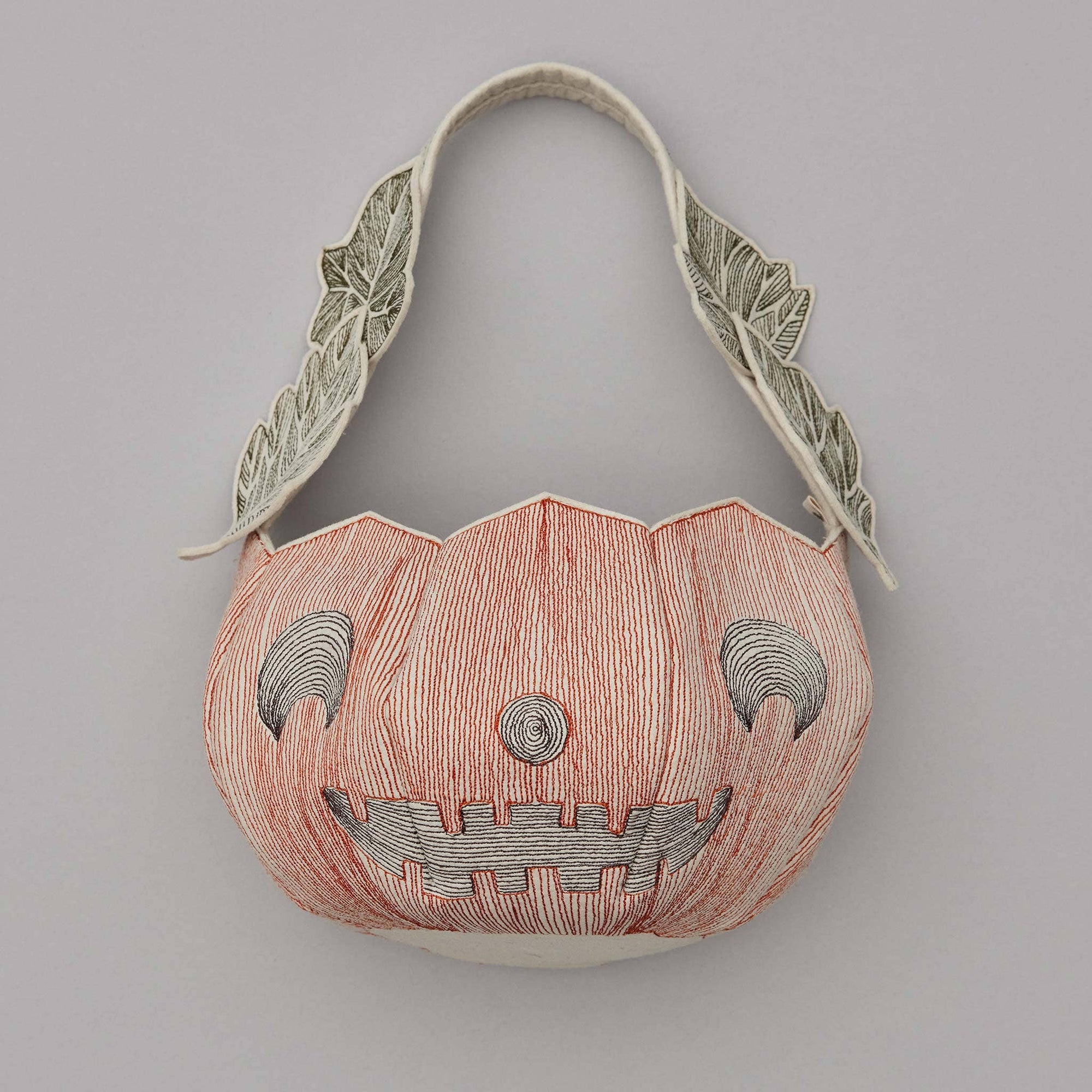 Pumpkin-shaped bag with a face design on a gray background