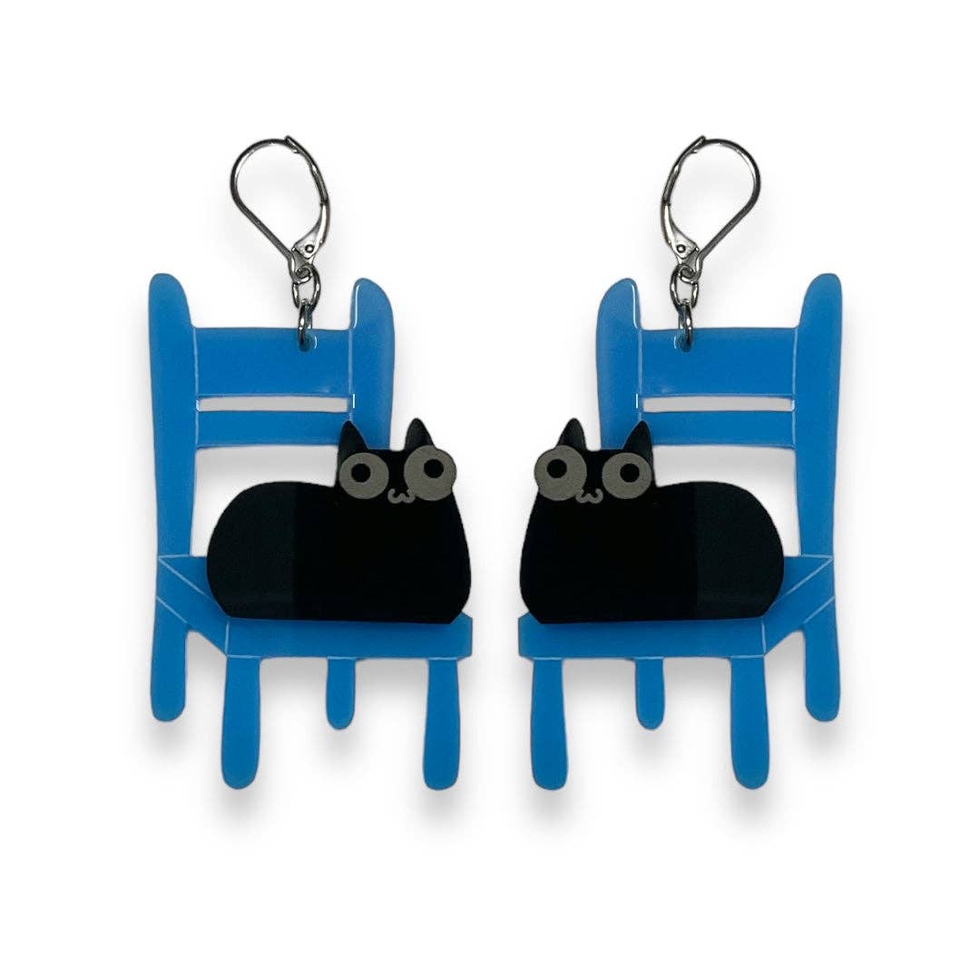 Pair of earrings with black cat designs on blue chairs against a white background