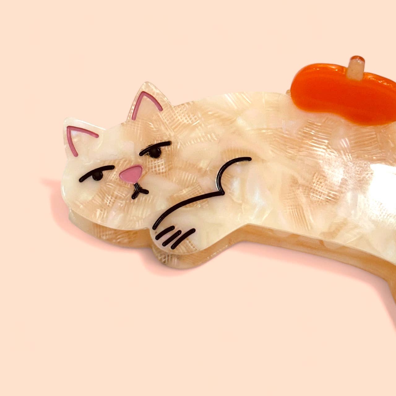 hair clip with a cat design and an apple on a pink background