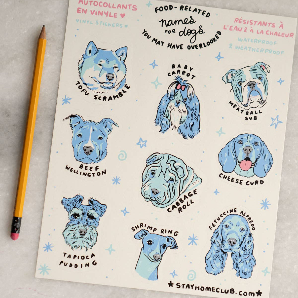 Sheet of dog-themed stickers with blue illustrations on a gray surface with a pencil.