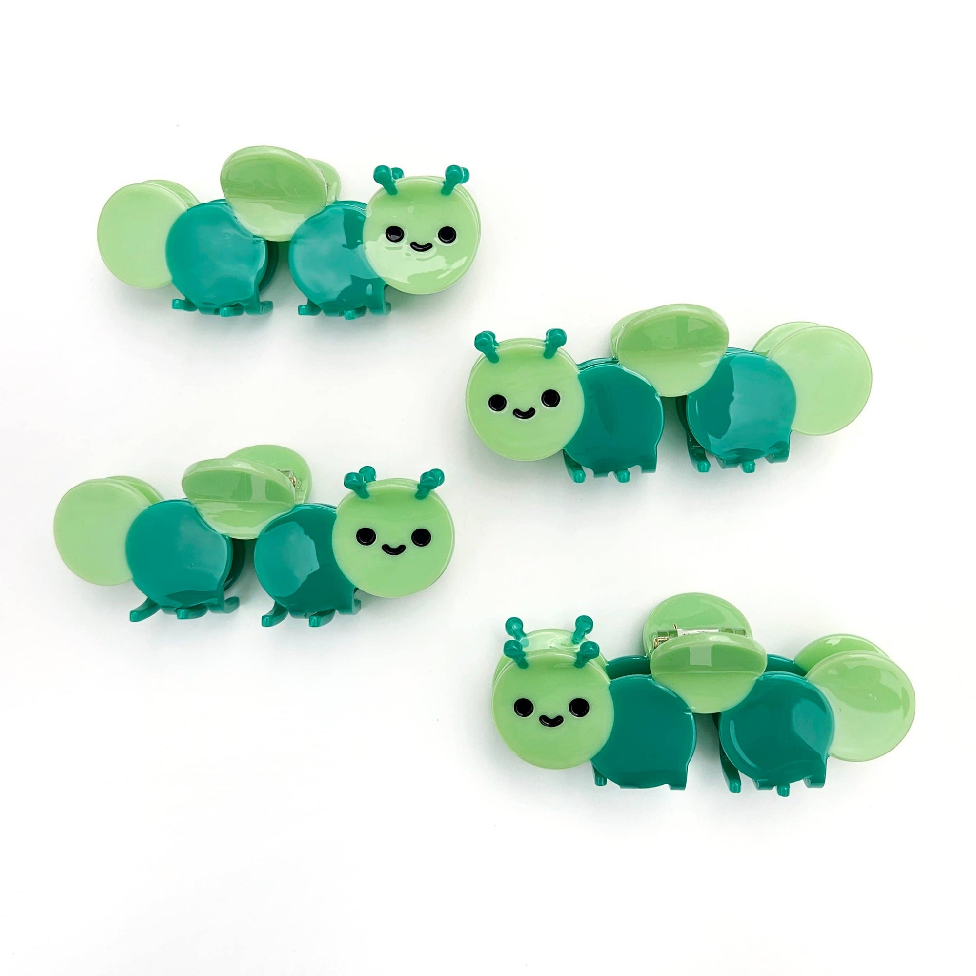 Set of green and teal caterpillar-shaped clips on a white background
