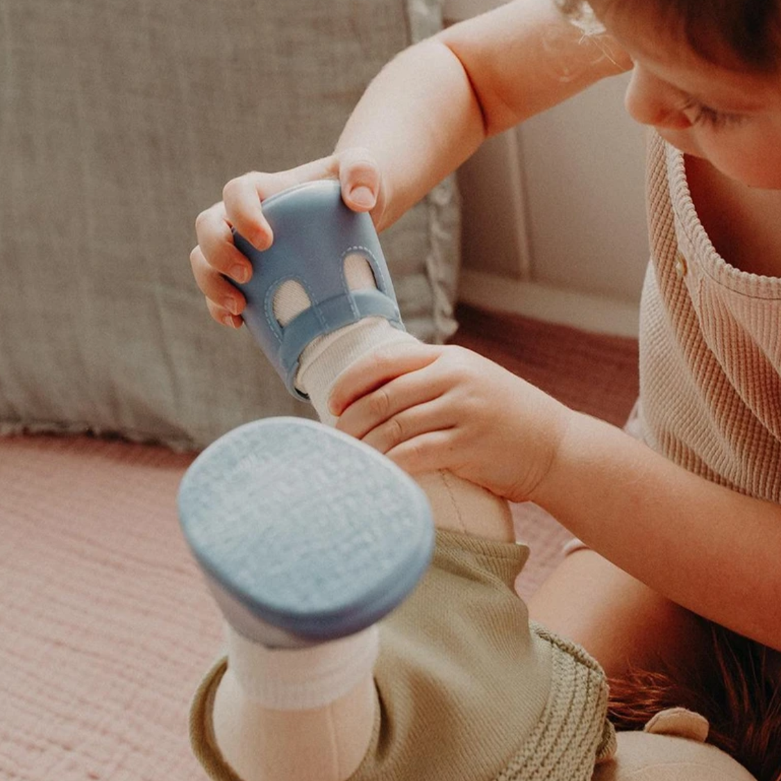 chold putting blue shoes on doll