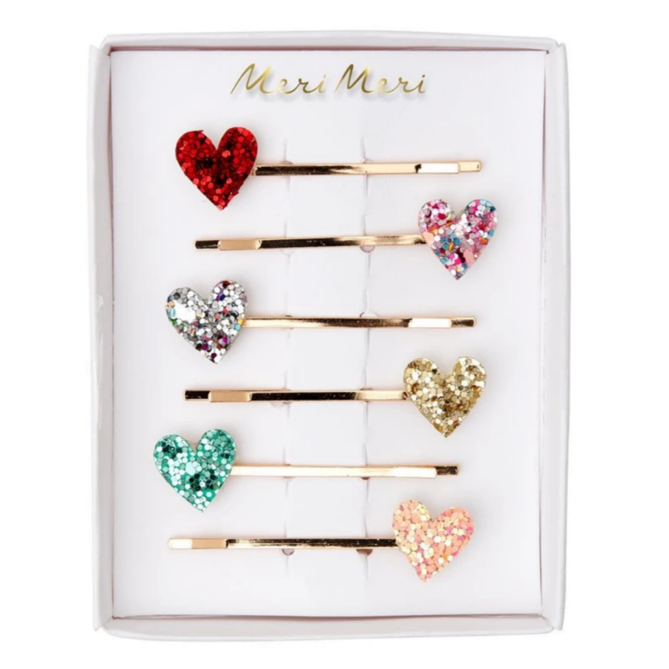 A set of six heart-shaped glitter hair slides on a white background, presented in a box with 'Merry' written on it.
