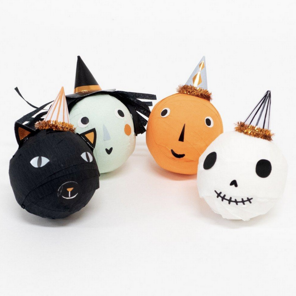 Four Halloween themed surprise balls with different designs including a witch, skull, black cat, and pumpkin, each topped with a matching hat.