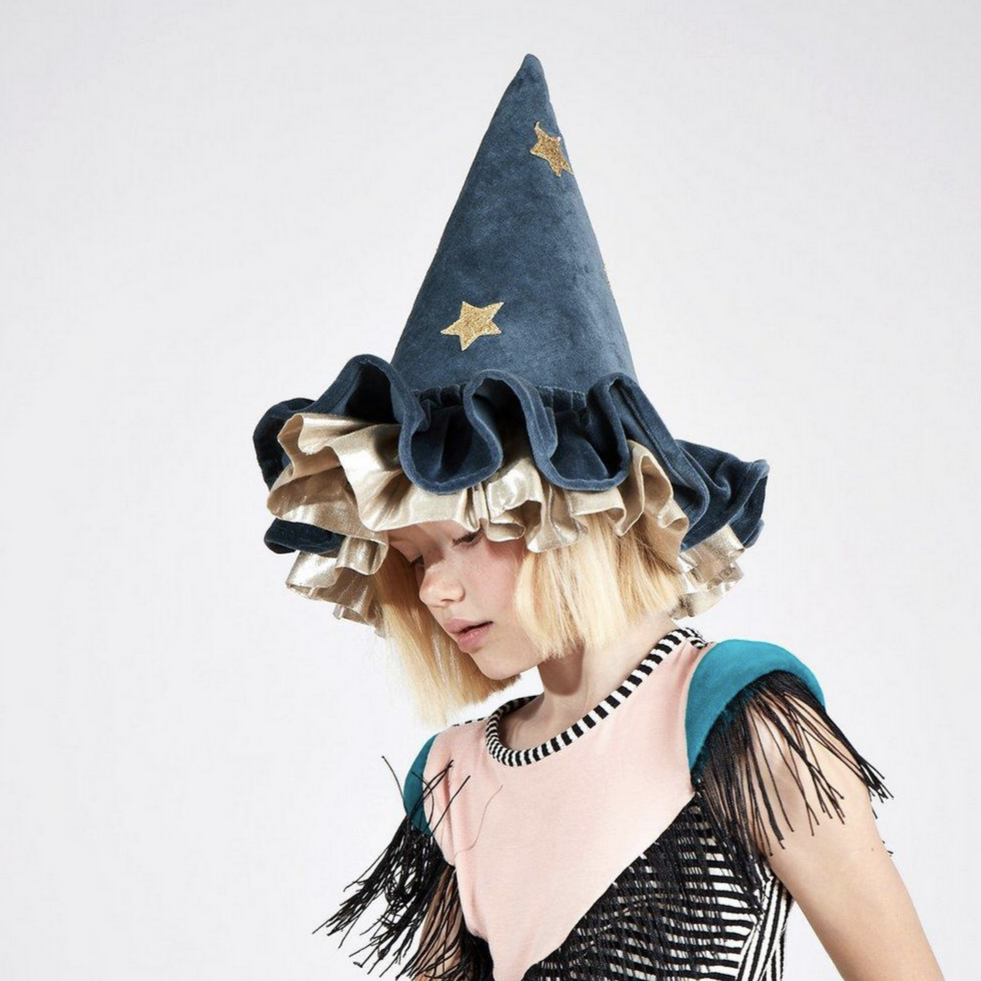 A person wearing a blue velvet wizard/witch hat with ruffle details and gold glitter embellishments.