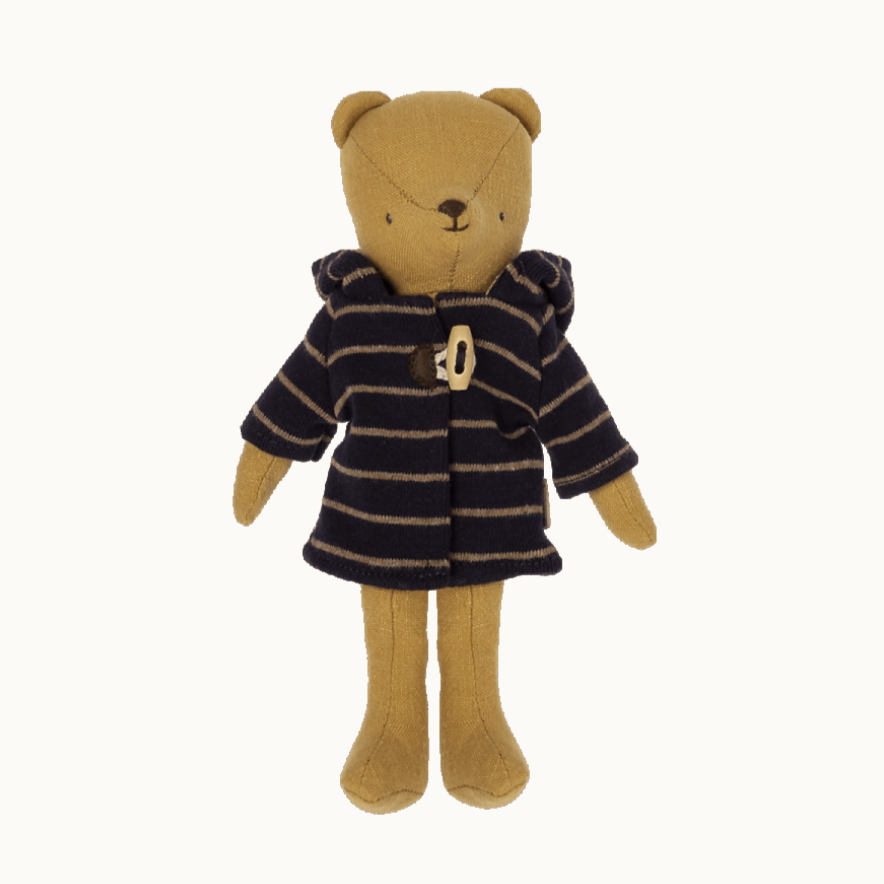 A teddy bear wearing a striped navy and beige duffle coat with a hood.