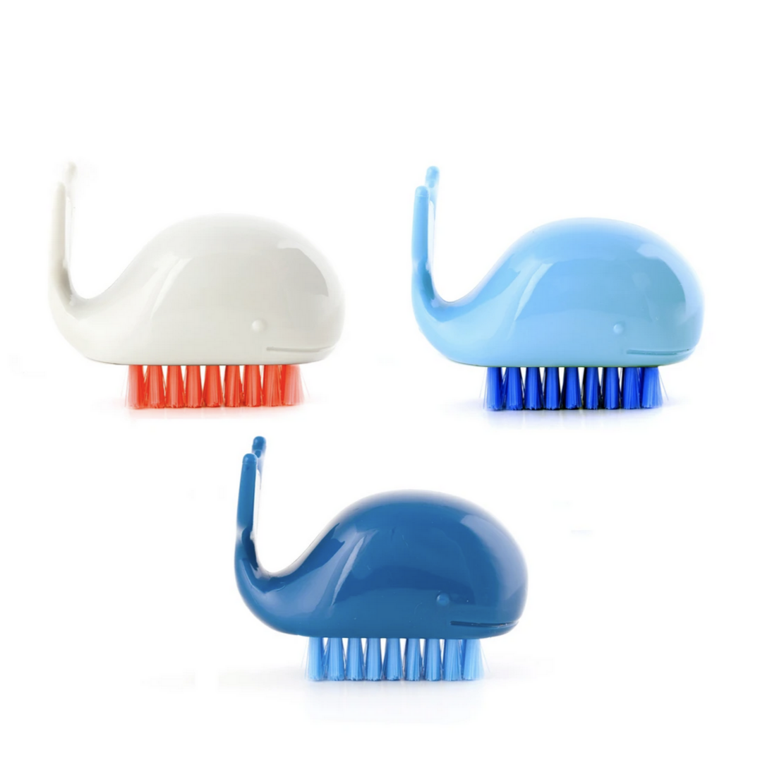 A set of three whale-shaped nail brushes in white, blue, and blue colors with red and blue bristles.