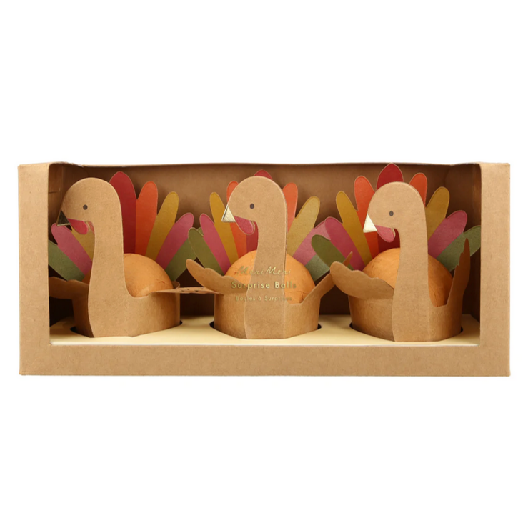A pack of three brown crepe paper surprise balls with 3D turkey designs, wrapped in brown crepe paper, with shiny gold foil details on a white background.