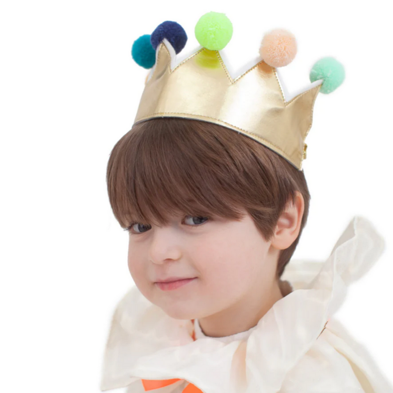 A child wearing a gold pompom crown with multicolored pompoms, designed to resemble a king or queen's crown.