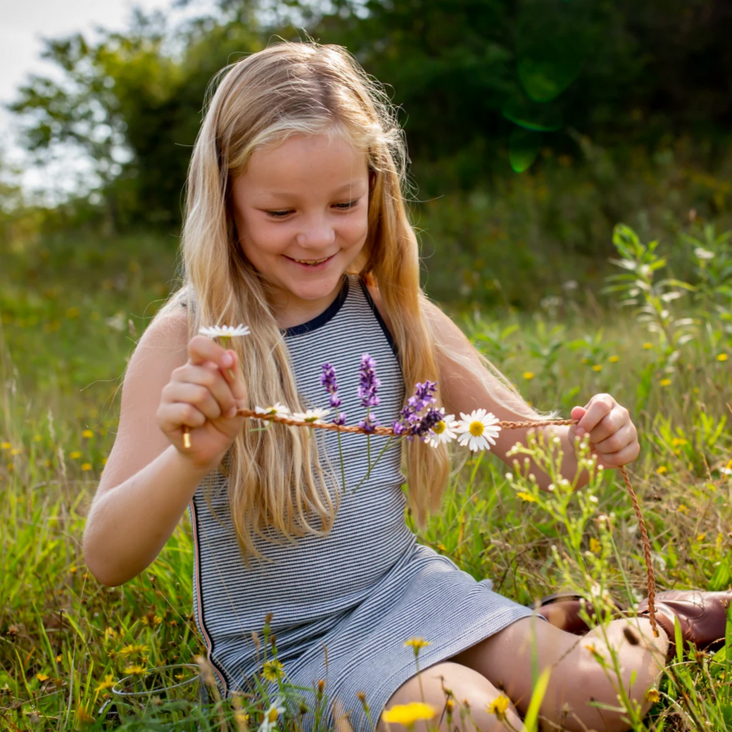 little girl looking at necklace after she's added flowers