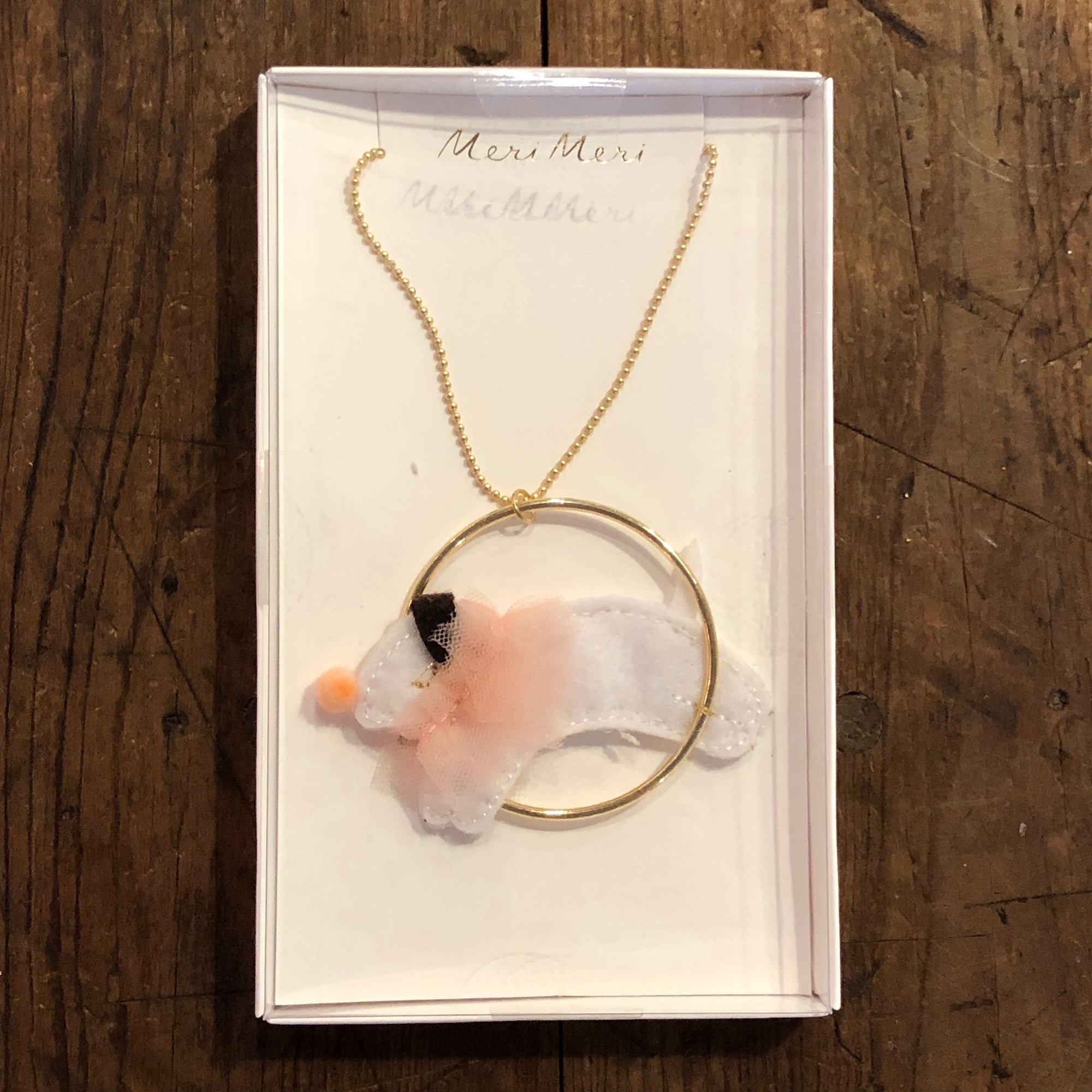 white dog jumping through golden hoop necklace